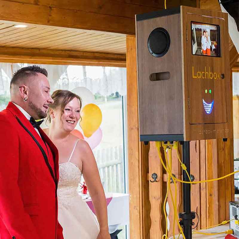 Brautpaar lacht neben der Lachbox auf einer Hochzeit